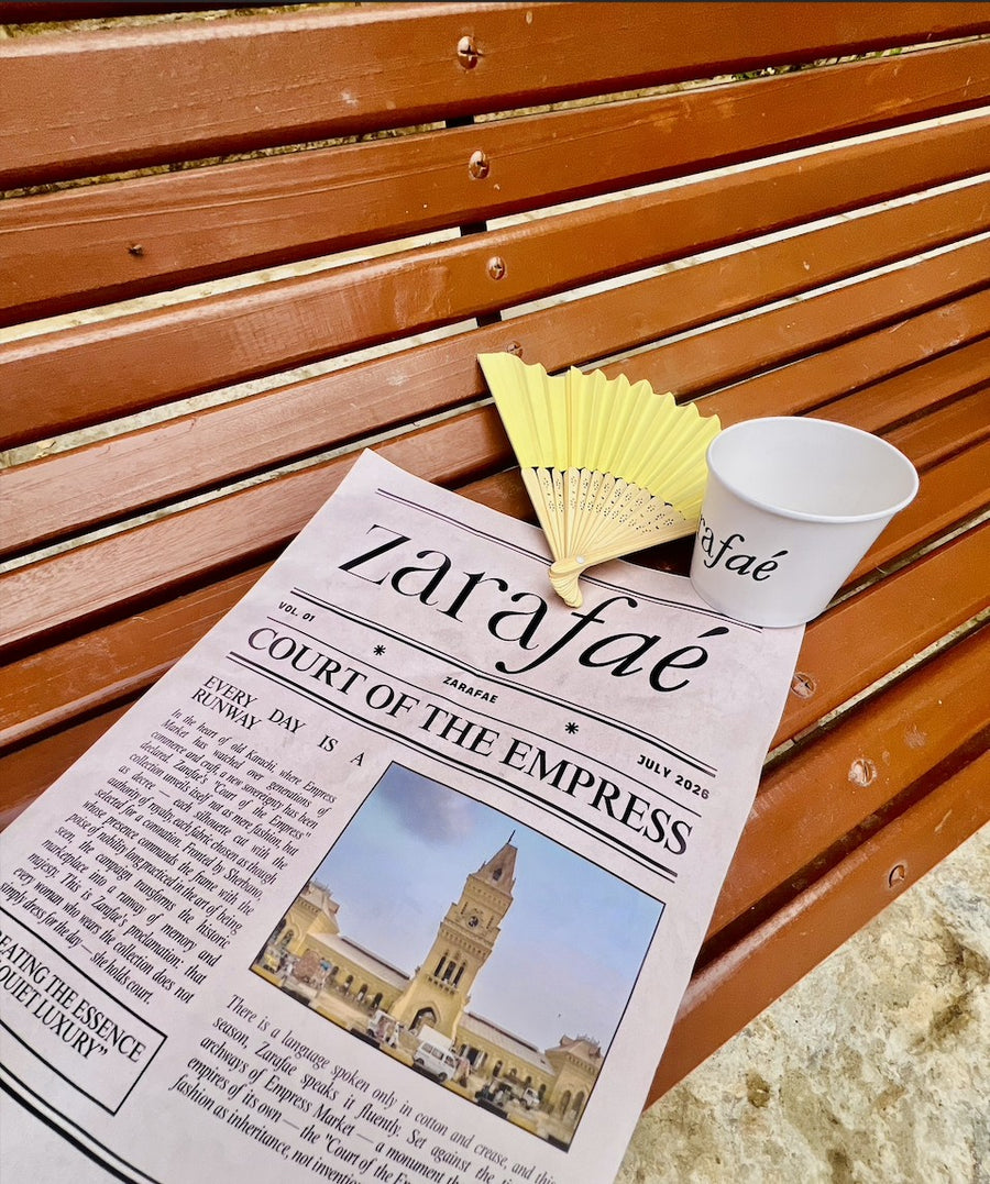 The zarafaé newspaper, Court of the Empress, on a bench beside a paper fan and a zarafaé cup